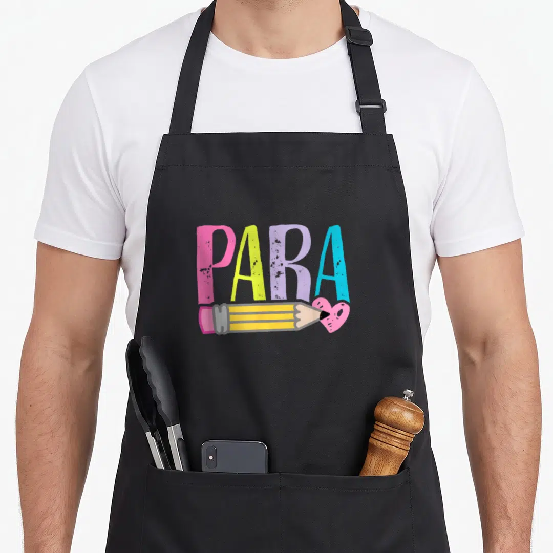 Colorful teacher apron - PARA text in pink yellow purple blue above horizontal pencil and pink heart — shown on a black cotton canvas apron against a white background