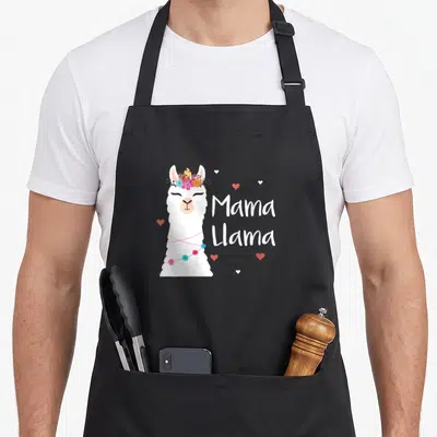 Llama mother's day aprons - White cartoon llama with flower crown and Mama Llama text surrounded by hearts — shown on a black cotton canvas apron against a white background