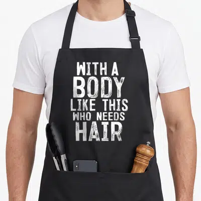 Funny body hair apron - White distressed text WITH A BODY LIKE THIS WHO NEEDS HAIR stacked in five lines — shown on a black cotton canvas apron against a white background
