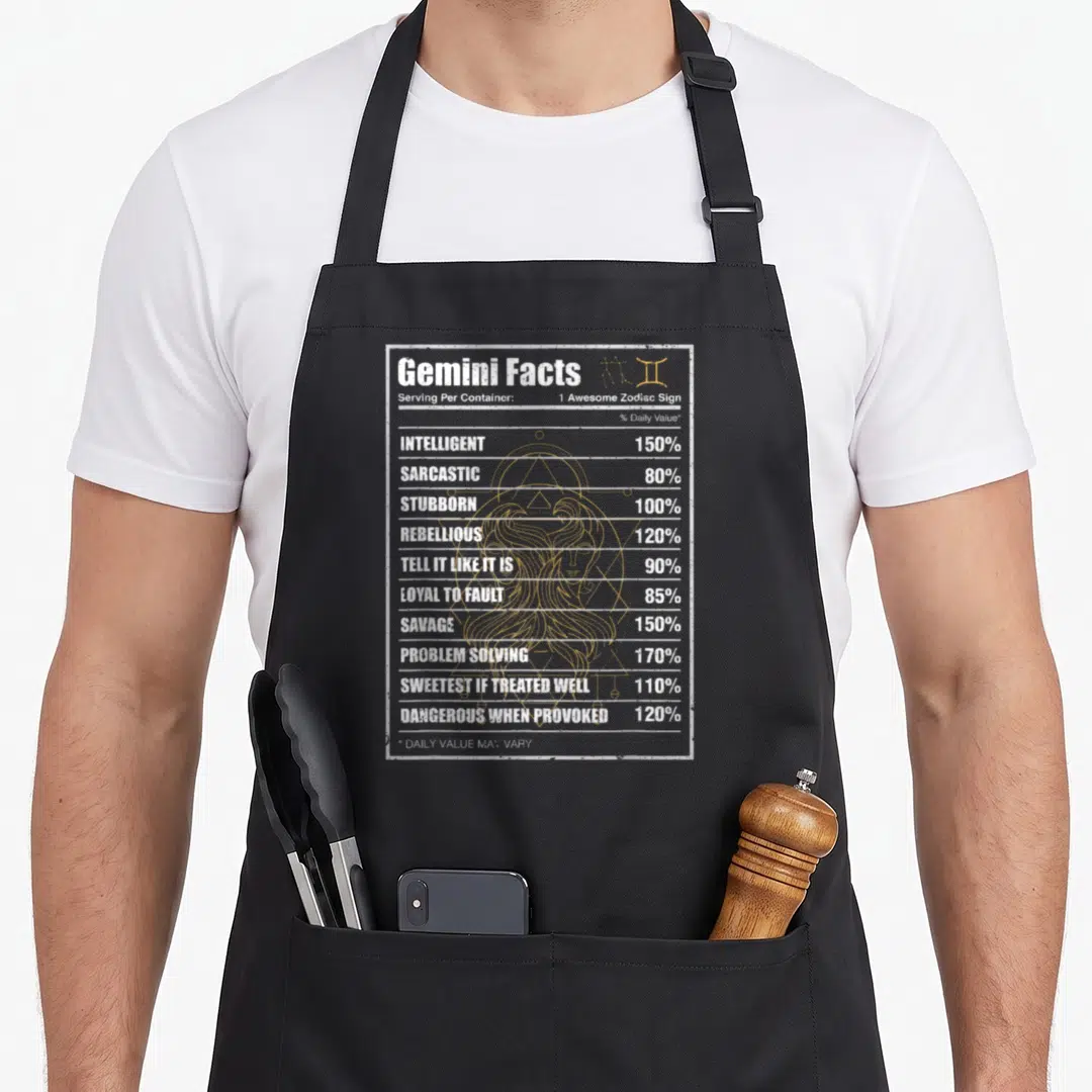 Fact horoscope zodiac aprons - Retro nutrition label with white text listing Gemini traits over a gold line-art woman — shown on a black cotton canvas apron against a white background