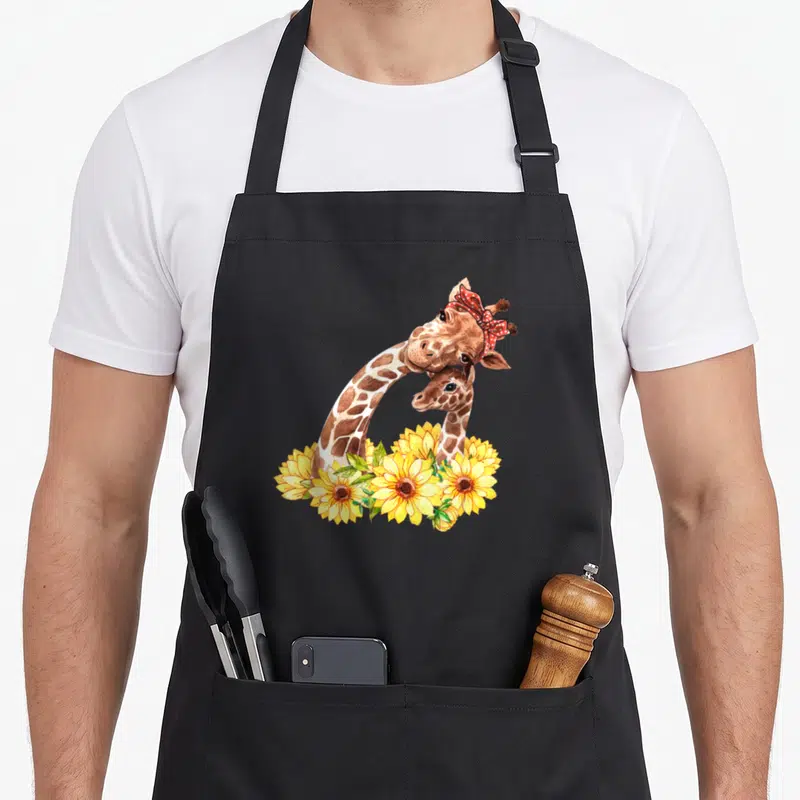 Sunflower giraffe apron - Two giraffes with red bandana and yellow sunflowers in watercolor style — shown on a black cotton canvas apron against a white background