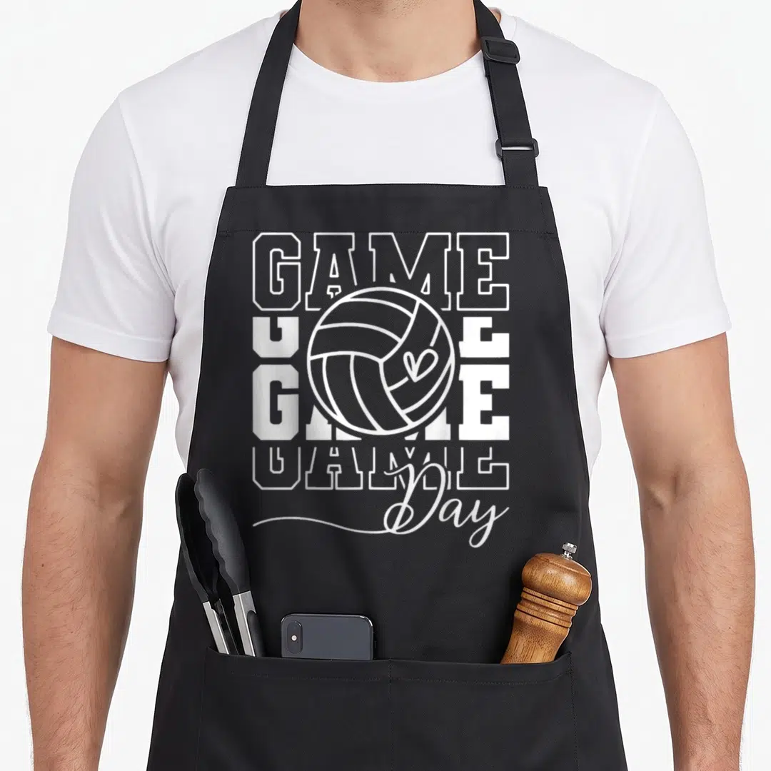 Volley game aprons - White block letters GAME and script Day surrounding a volleyball outline — shown on a black cotton canvas apron against a white background