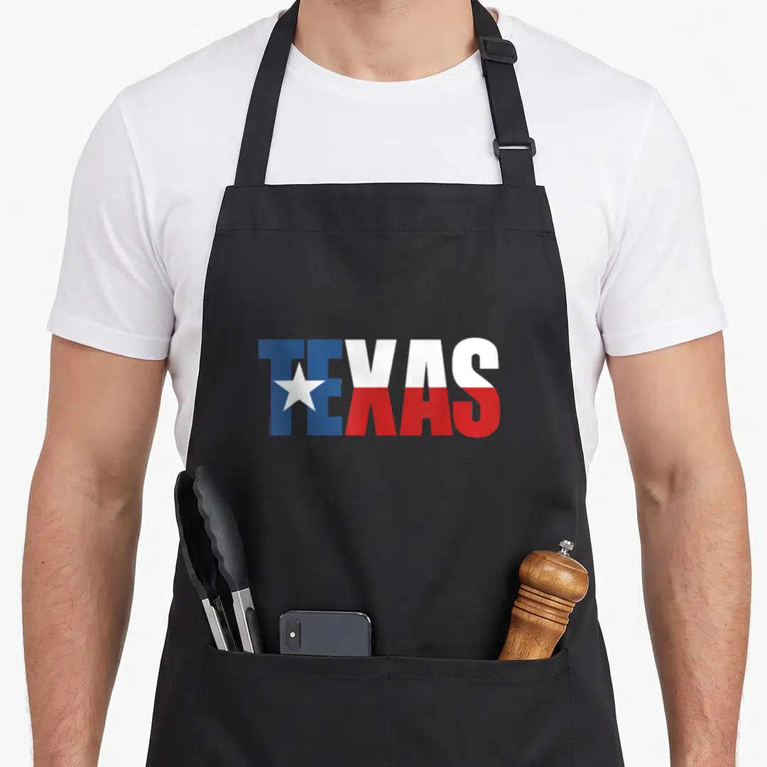 Flag texas apron - TEXAS word art filled with blue white red flag colors and lone star — shown on a black cotton canvas apron against a white background