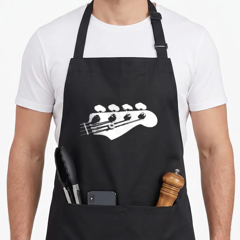 Bassist bassoon apron - White distressed bass guitar headstock graphic centered on grey background — shown on a black cotton canvas apron against a white background