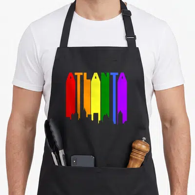 Atlanta gay pride apron - ATLANTA text in rainbow colors forming a city skyline silhouette — shown on a black cotton canvas apron against a white background