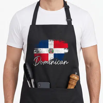Dominican republic pride apron - Distressed Dominican flag with red blue white blocks and script text Dominican — shown on a black cotton canvas apron against a white background