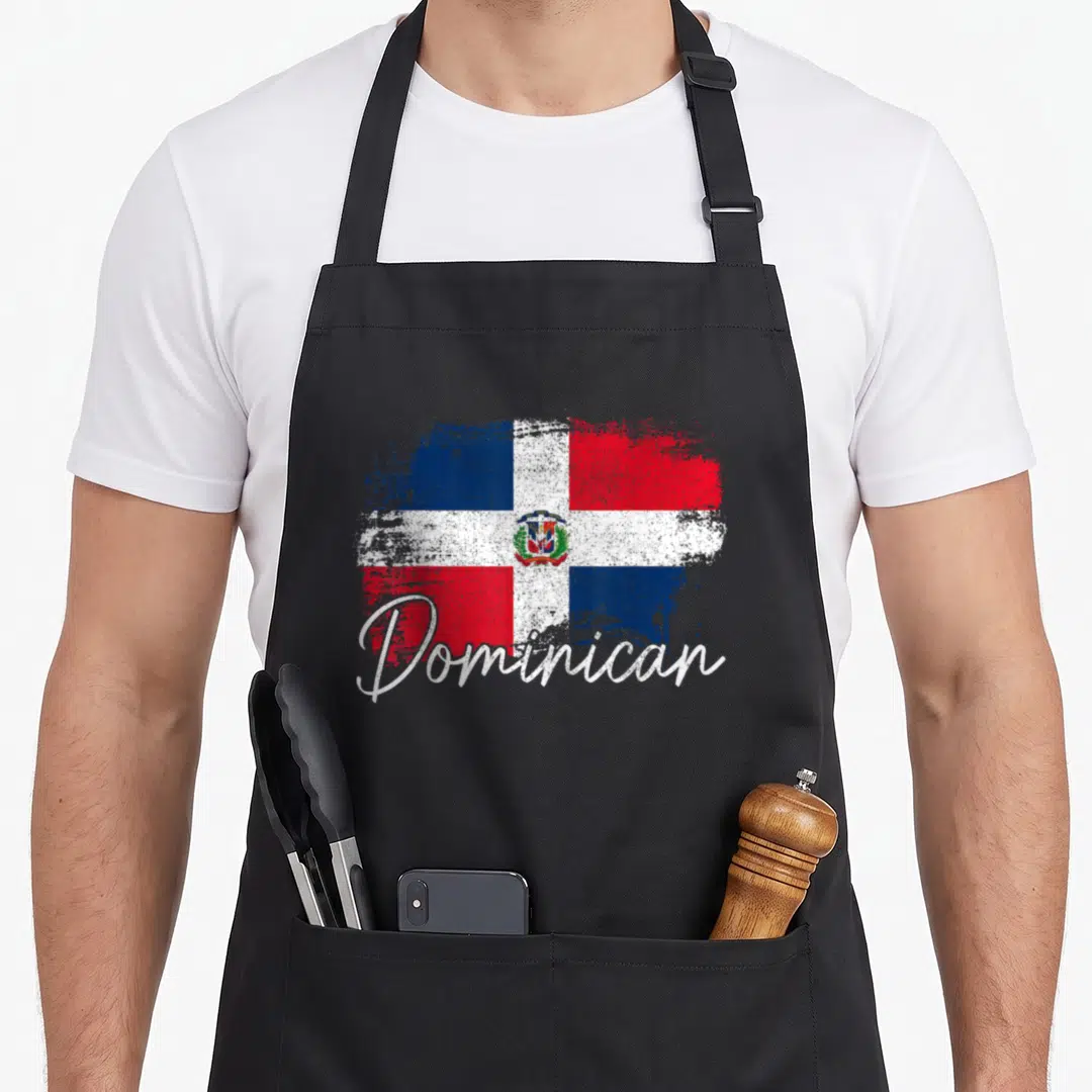 Dominican republic pride apron - Distressed Dominican flag with red blue white blocks and script text Dominican — shown on a black cotton canvas apron against a white background