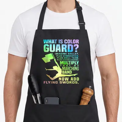 Guard swing quotes apron - Rainbow text defining color guard with a leaping performer silhouette holding a flag — shown on a black cotton canvas apron against a white background