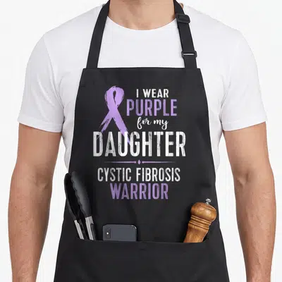 Daughter cystic fibrosis awareness apron - Purple ribbon and I WEAR PURPLE for my DAUGHTER CYSTIC FIBROSIS WARRIOR text — shown on a black cotton canvas apron against a white background