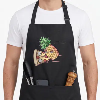 Belong pineapple apron - Cartoon pineapple hugging pizza slice with text SHHH NO ONE NEEDS TO KNOW — shown on a black cotton canvas apron against a white background