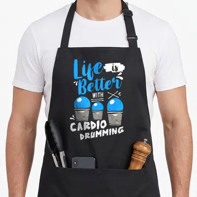 Better cardio apron - Stacked text Life is Better With Cardio Drumming above three blue balls in grey buckets — shown on a black cotton canvas apron against a white background