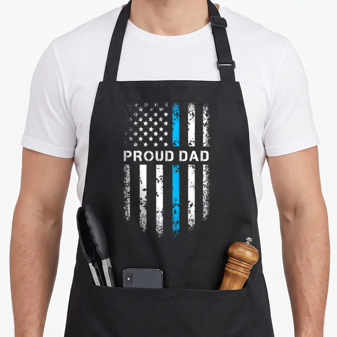 Law patriotic apron - PROUD DAD text over distressed flag with vertical white and blue stripes — shown on a black cotton canvas apron against a white background