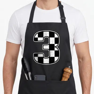 Birthday three car apron - Large checkered number 3 in black and white racing pattern — shown on a black cotton canvas apron against a white background