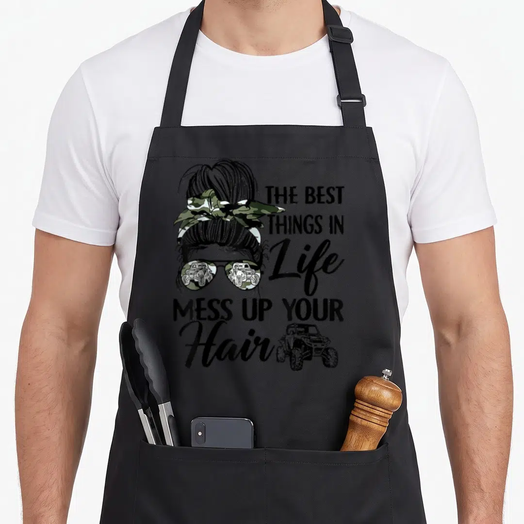 Mess utv hair apron - Woman's head with bun and camo bow, stacked text, UTV graphic, black green brown — shown on a black cotton canvas apron against a white background