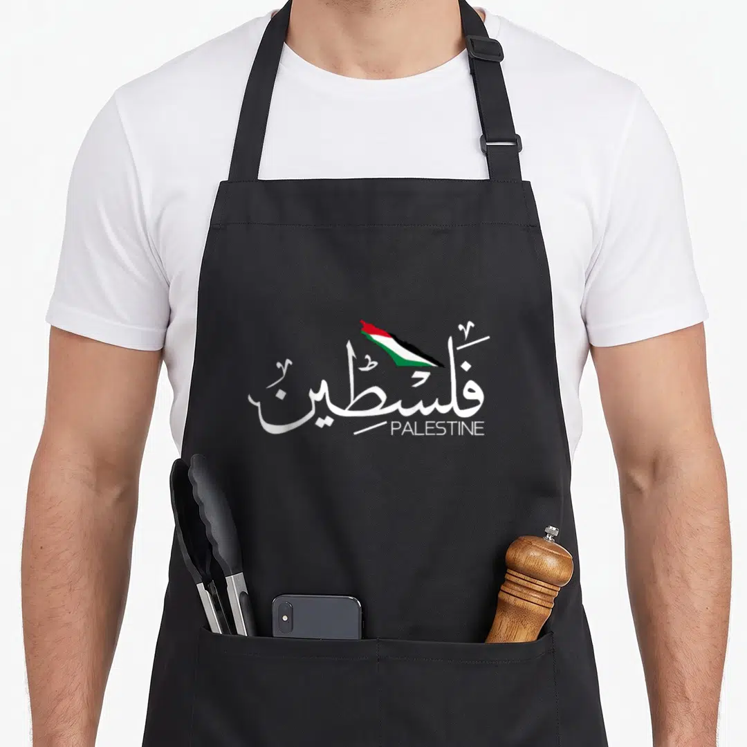 Arabic flag palestine apron - White Arabic calligraphy for Palestine with a small red green and black flag map above — shown on a black cotton canvas apron against a white background