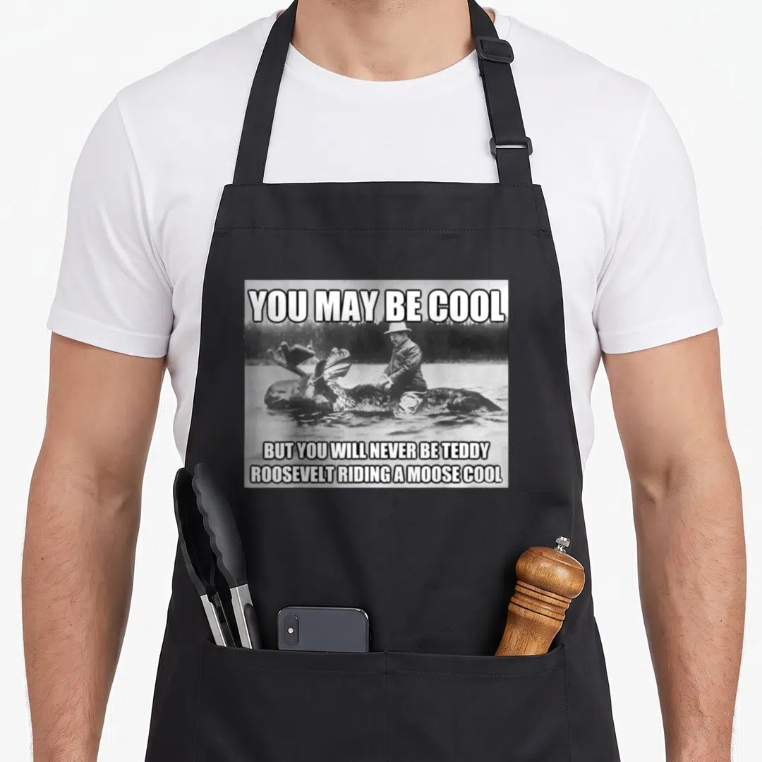 Hipster meme apron - Black and white photo of Teddy Roosevelt on a moose with sarcastic text — shown on a black cotton canvas apron against a white background