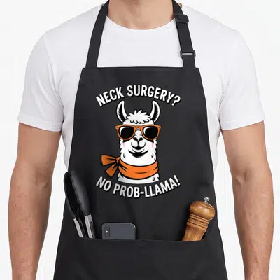 Recovering recovery day apron - Llama with orange sunglasses and scarf under neck surgery pun text — shown on a black cotton canvas apron against a white background