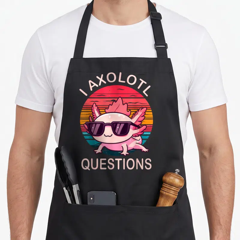 Sunglass axolotl question apron - Pink axolotl wearing sunglasses inside a striped circle with arched text I AXOLOTL — shown on a black cotton canvas apron against a white background