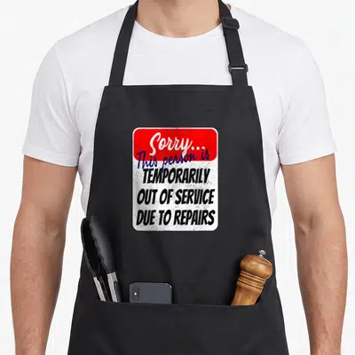Joint hip apron - Distressed sign reading Sorry this person is temporarily out of service due to repairs — shown on a black cotton canvas apron against a white background