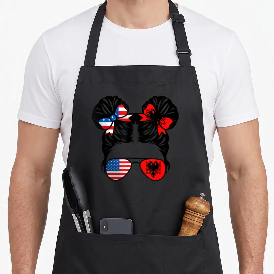 Albanian albania american flag apron - Minimalist woman silhouette with USA and Albanian flags in two buns — shown on a black cotton canvas apron against a white background