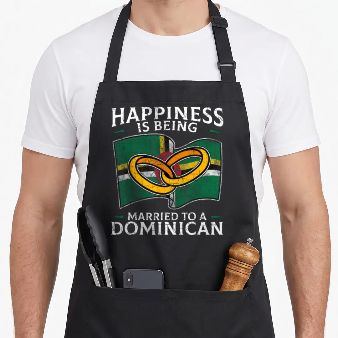 Dominica heritage aprons - Distressed text above waving flag with two interlocking gold rings — shown on a black cotton canvas apron against a white background