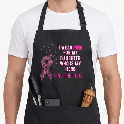 Cute daughter breast cancer awareness aprons - Pink awareness ribbon formed by small butterflies next to stacked text — shown on a black cotton canvas apron against a white background