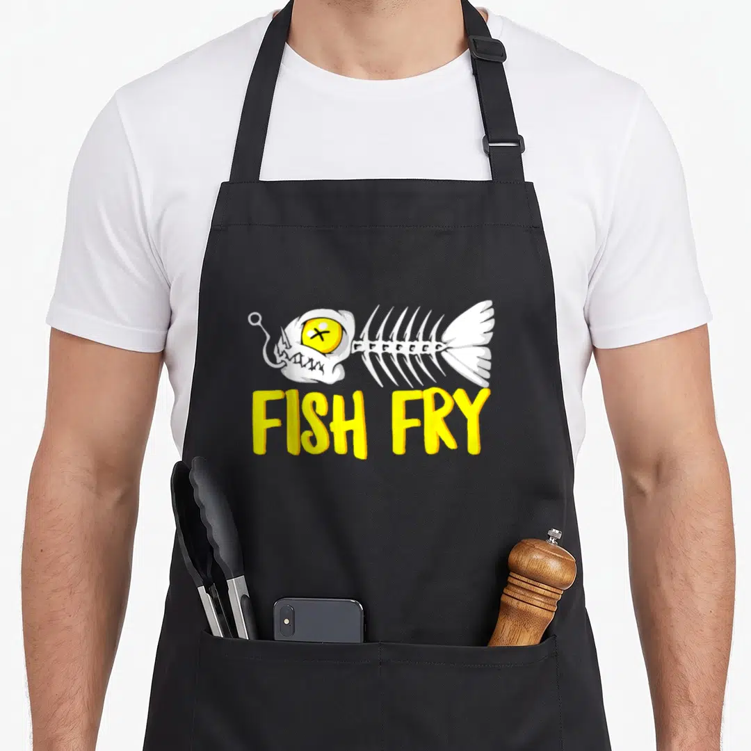 Fry old fashioned aprons - White fish skeleton with yellow eye above yellow FISH FRY text — shown on a black cotton canvas apron against a white background