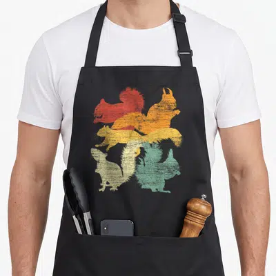 Forest squirrel aprons - Four stacked squirrel silhouettes in red orange yellow and green with distressed texture — shown on a black cotton canvas apron against a white background