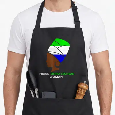 Sierra african apron - Brown woman silhouette wearing green white and blue headwrap with text below — shown on a black cotton canvas apron against a white background