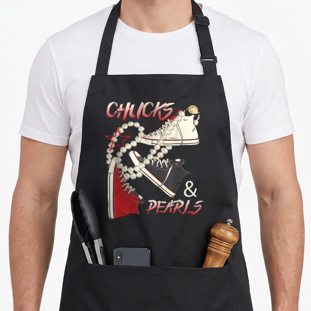 Chuck pearl apron - Three sneakers with pearl necklace and red star, CHUCKS & PEARLS text — shown on a black cotton canvas apron against a white background
