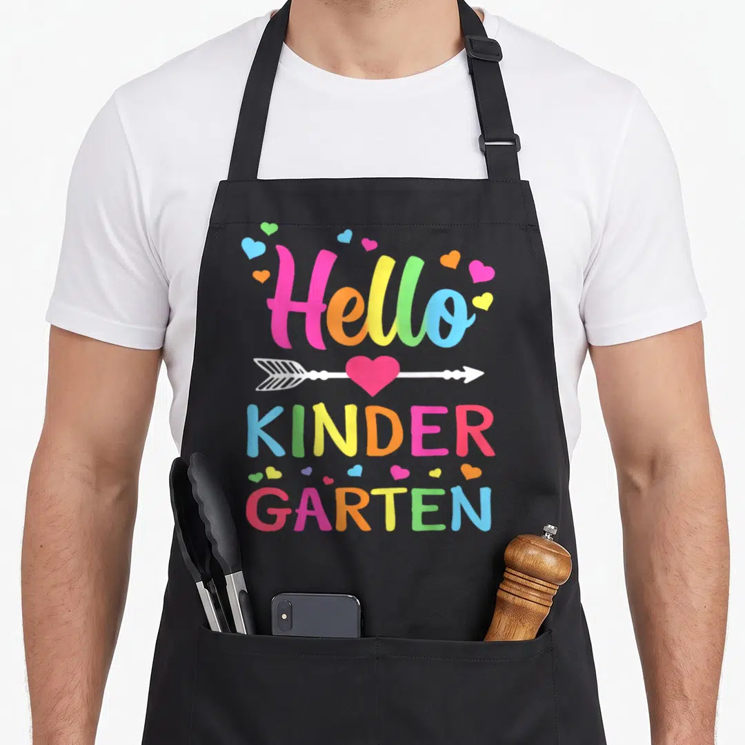 Hello kinder kindergarten teacher apron - Hello KINDER GARTEN text with arrow through heart and colorful scattered — shown on a black cotton canvas apron against a white background