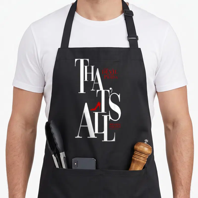 Priestly miranda apron - Vertical white text THAT'S ALL with red high heel shoe inside the letter — shown on a black cotton canvas apron against a white background