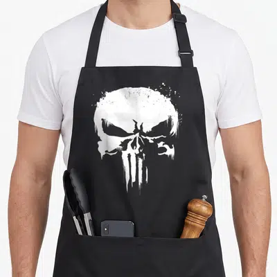 Punisher paint splatter apron - Single large distressed white skull graphic with dripping paint effects centered — shown on a black cotton canvas apron against a white background