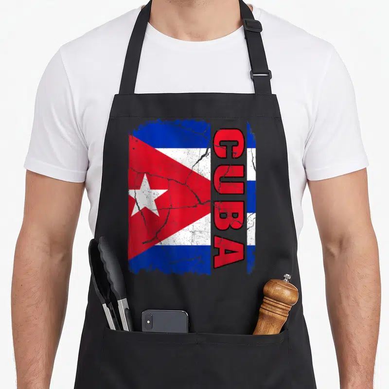 Cuban flag pride apron - Distressed Cuban flag print with vertical red CUBA text on blue white and red background — shown on a black cotton canvas apron against a white background