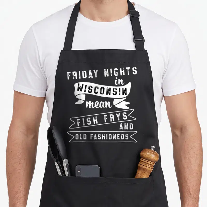 Fish old fashioned aprons - Distressed text reading FRIDAY NIGHTS in WISCONSIN mean FISH FRYS AND OLD FASHIONEDS — shown on a black cotton canvas apron against a white background