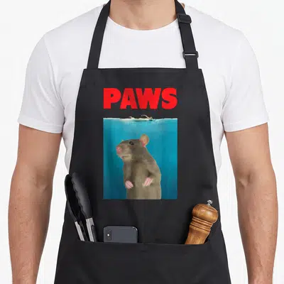 Paw rat lover apron - Red PAWS text above a brown rat swimming underwater in blue water — shown on a black cotton canvas apron against a white background