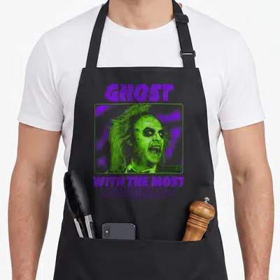 Neon ghost apron - GHOST text above green man portrait in frame, mirrored WITH THE MOST below — shown on a black cotton canvas apron against a white background