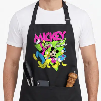 Neon friends cooking apron - Mickey and friends cartoon group shot in pink green yellow and blue on black apron — shown on a black cotton canvas apron against a white background