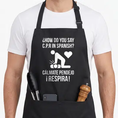 Calmate spanish aprons - White CPR silhouette and Spanish text asking how to say CPR in Spanish — shown on a black cotton canvas apron against a white background