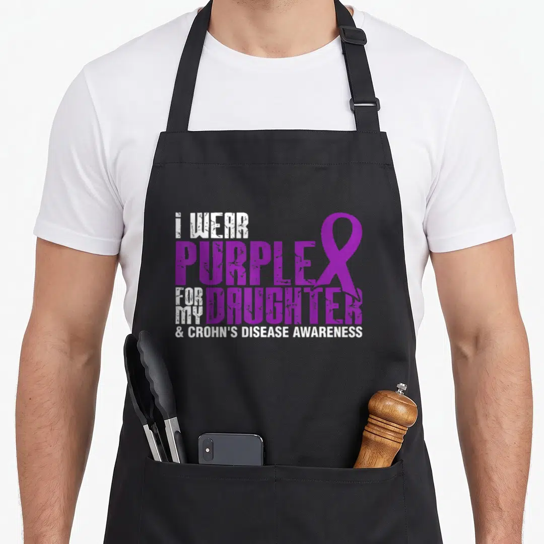 Daughter crohns awareness apron - Purple and white stacked text reading I WEAR PURPLE FOR MY DAUGHTER with a ribbon — shown on a black cotton canvas apron against a white background