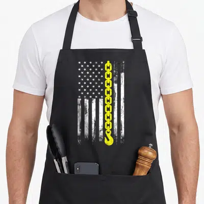 Line flag truck apron - Distressed white flag with vertical yellow chain and hook graphic — shown on a black cotton canvas apron against a white background