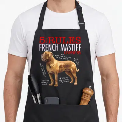 Rule french apron - Cartoon tan mastiff surrounded by four white rule phrases under red and white stacked title text — shown on a black cotton canvas apron against a white background