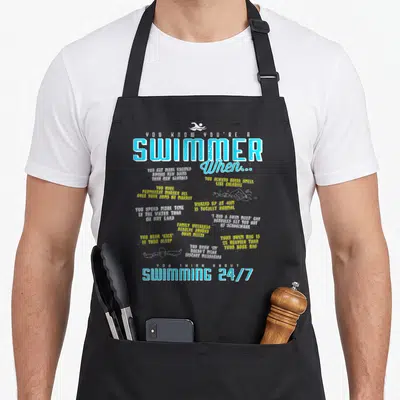List swimmer apron - Swimmer list text with white gear silhouettes in blue yellow and white on black — shown on a black cotton canvas apron against a white background