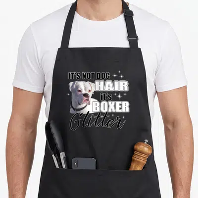 Hair boxer dog apron - White boxer dog photo with IT'S NOT DOG HAIR text and sparkles — shown on a black cotton canvas apron against a white background