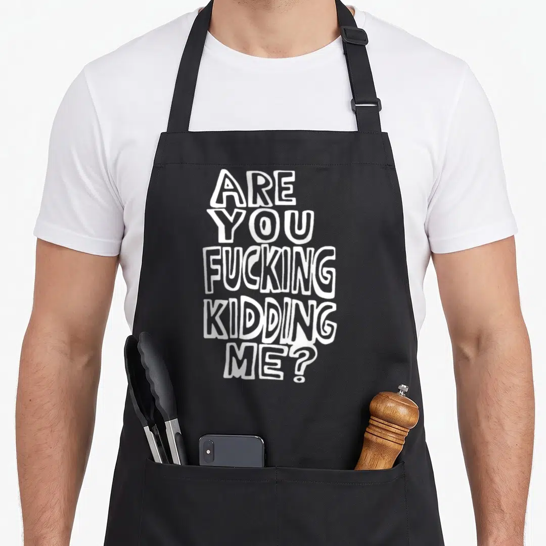 Trying fools apron - White stacked text reading Are You Kidding Me in bubbly font — shown on a black cotton canvas apron against a white background