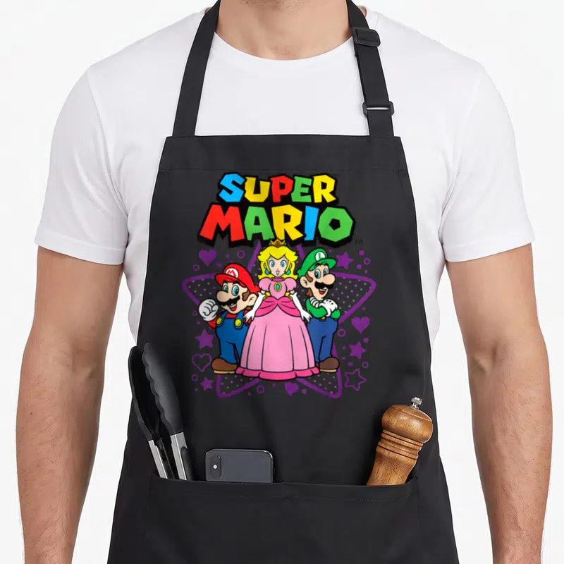 Trio peach apron - Super Mario, Peach, and Luigi in front of purple star with hearts and colorful text — shown on a black cotton canvas apron against a white background