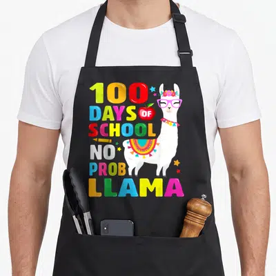 Probllama school apron - Cartoon llama with 100 DAYS OF SCHOOL NO PROB LLAMA text and crayon — shown on a black cotton canvas apron against a white background