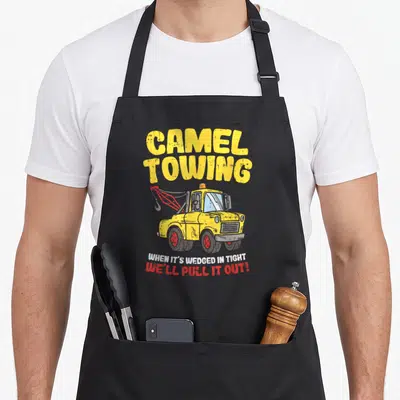 Camel truck apron - Distressed yellow tow truck with CAMEL TOWING text and red hook — shown on a black cotton canvas apron against a white background