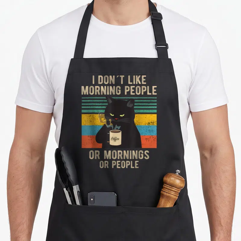 Hate cat apron - Black cat holding coffee mug against teal yellow and red stripes with sarcastic text — shown on a black cotton canvas apron against a white background