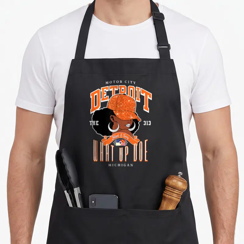 Unapologetically detroit apron - Cartoon woman orange cap 313 text Motor City Detroit Black Sexy What Up Doe flag — shown on a black cotton canvas apron against a white background